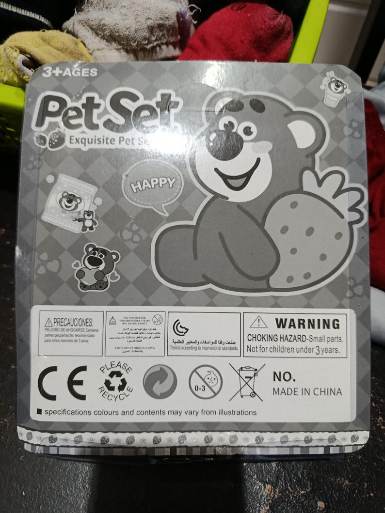 May include: A gray cardboard box with a cartoon bear holding a strawberry. The box has the words "Pet Set" and "Happy" on it. The box also has a warning label that says "Choking Hazard - Small parts. Not for children under 3 years."