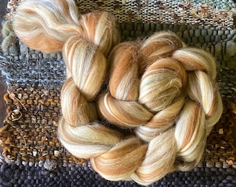 May include: A braided bundle of brown and white wool roving. The roving is arranged in a circular shape, with the ends of the braid tucked into the center.
