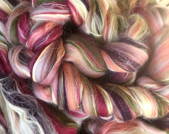 May include: A close-up of a colorful, hand-spun yarn with shades of pink, purple, green, and white. The yarn is soft and fluffy, and it is perfect for knitting or crocheting.
