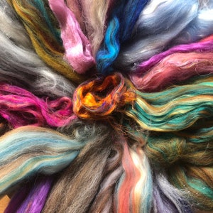 May include: A collection of colorful yarn fibers in various shades of blue, green, pink, orange, and brown. The fibers are arranged in a circular pattern, creating a visually appealing and textured display.