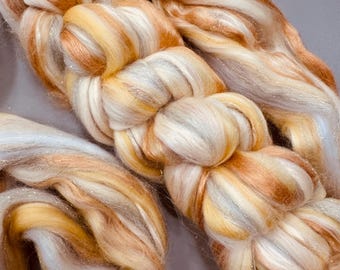 May include: A close-up of a bundle of colorful yarn with white, yellow, and orange strands. The yarn has a shimmery, iridescent quality.