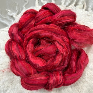 May include: A bundle of red and orange silk fiber, also known as silk roving, for spinning or felting.
