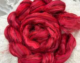May include: A bundle of red and orange silk fiber, also known as silk roving, for spinning or felting.