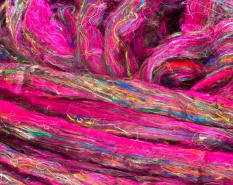 May include: Close-up of a pile of pink, blue, green, and yellow yarn. The yarn is very fine and has a soft, fuzzy texture.