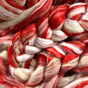 May include: Close-up of a braided yarn with red, white, and gold stripes. The yarn is soft and fluffy, and it would be perfect for knitting or crocheting.