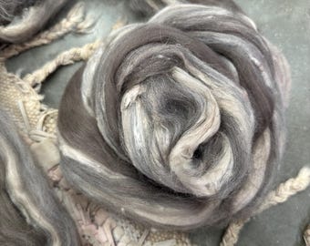 May include: A close-up of a bundle of brown and white wool roving. The wool is soft and fluffy, and it is perfect for spinning or felting.