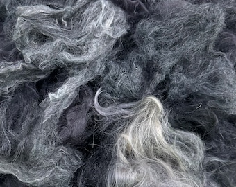 May include: A close-up of a pile of black and white wool fibers. The fibers are soft and fluffy, and they are perfect for spinning or felting.