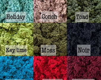 May include: A grid of nine textured fabric swatches in various colors, each labeled with text: Holiday (teal), Conch (dusty pink), Toad (olive), Key lime (bright green), Moss (dark green), Noir (black), Turkish (blue), Scarlet (red), and Wine cup (maroon).