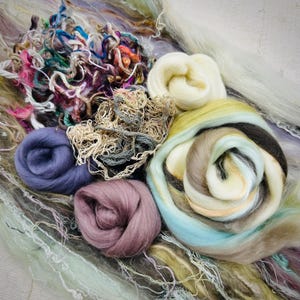 May include: A collection of colorful wool fibers in various shades of blue, green, brown, and purple. The fibers are arranged in a circular pattern, creating a visually appealing display.