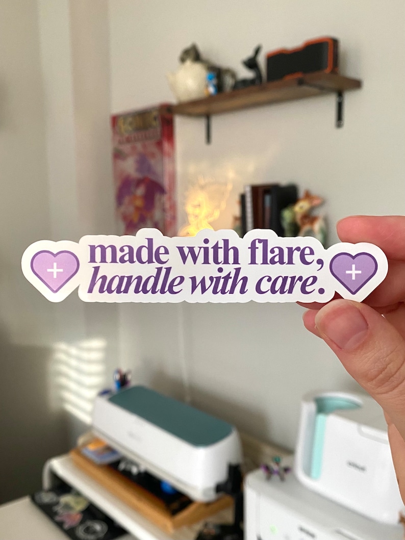 May include: A white sticker with purple hearts and the text "made with flare, handle with care."