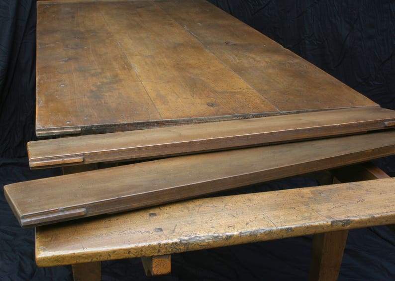 Puede incluir: Una mesa de madera con una extensi&oacute;n de hoja ca&iacute;da. La mesa est&aacute; hecha de madera marr&oacute;n oscura y tiene un acabado r&uacute;stico. La mesa est&aacute; en posici&oacute;n cerrada, con la hoja ca&iacute;da plegada hacia abajo.