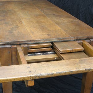Puede incluir: Una mesa de madera con una extensi&oacute;n de hoja abatible. La mesa est&aacute; hecha de madera maciza y tiene un acabado natural. La mesa est&aacute; en posici&oacute;n extendida, mostrando las hojas que se almacenan debajo de la parte superior.