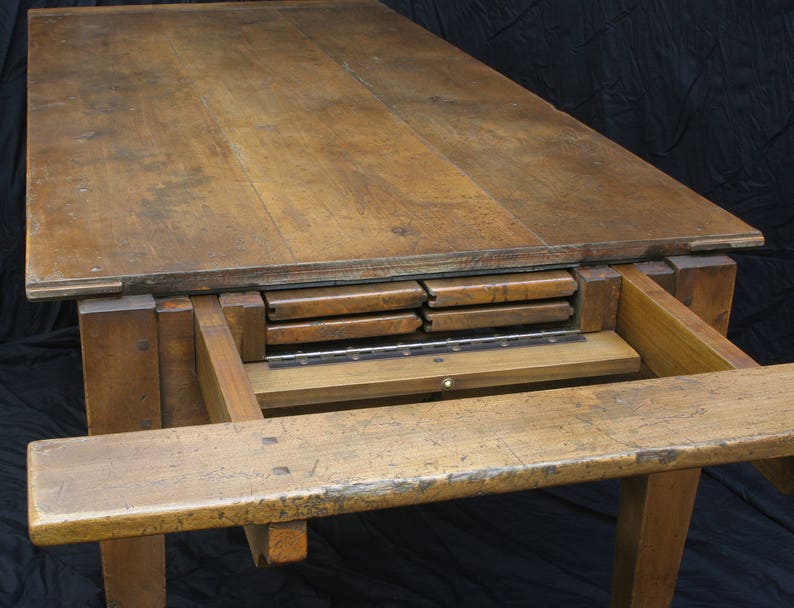 Puede incluir: Una mesa de madera con una extensi&oacute;n de hoja abatible. La mesa tiene un acabado de madera natural y est&aacute; hecha de madera maciza. La mesa est&aacute; en posici&oacute;n extendida, mostrando las hojas que se almacenan debajo de la parte superior.