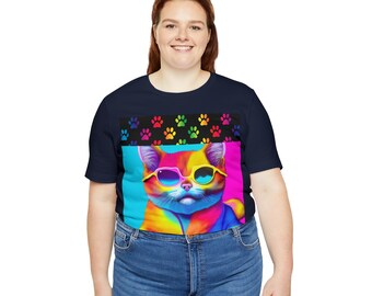 Op de afbeelding: Marineblauw T-shirt met een kleurrijke kat met zonnebril. De kattenafbeelding staat tegen een turquoise en roze achtergrond. Boven de kat bevindt zich een zwarte band met kleurrijke pootafdrukken.
