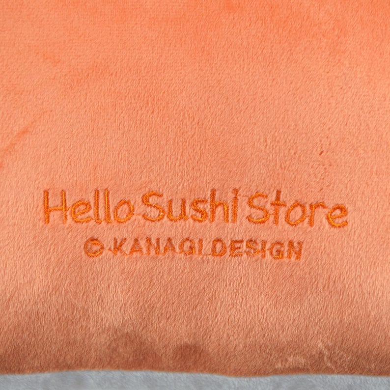May include: Orange fabric with the text "Hello Sushi Store" and "&copy; KANAGI DESIGN" embroidered in orange thread.