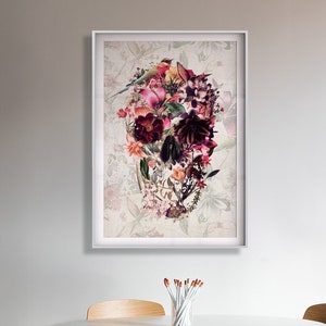 May include: A framed print of a skull made of flowers. The skull is made of pink, red, and purple flowers. The background is a light beige with a floral pattern.