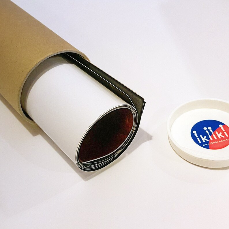 Puede incluir: Un p&oacute;ster o impresi&oacute;n enrollado est&aacute; dentro de un tubo de cart&oacute;n con una tapa blanca. La tapa tiene un logotipo rojo y azul con el texto "ikili.com.tr".
