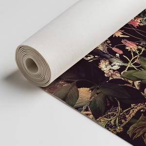 May include: A rolled canvas print featuring a dark floral pattern with a variety of flowers, leaves, and vines in shades of pink, white, and green on a black background.