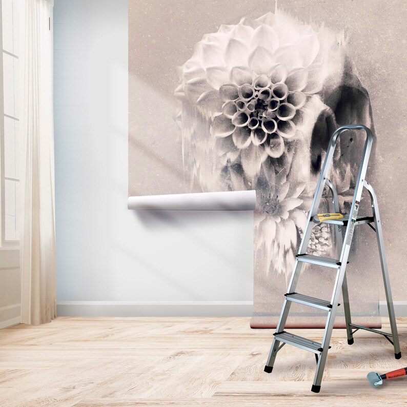 May include: A floral wallpaper with a skull design is partially installed on a wall. A silver step ladder and tools are in the room. The room has a light wood floor and a window with a white curtain.