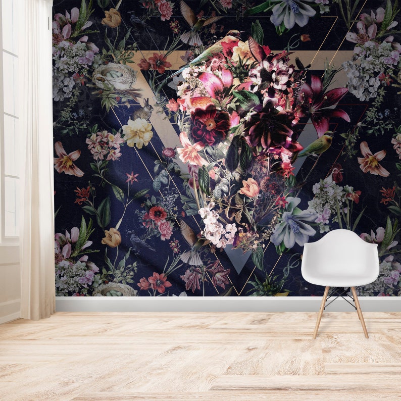 May include: Dark navy floral wallpaper with a large geometric design. The wallpaper features a variety of flowers in shades of pink, red, and purple, with green leaves and small birds. A white chair sits in front of the wallpaper.