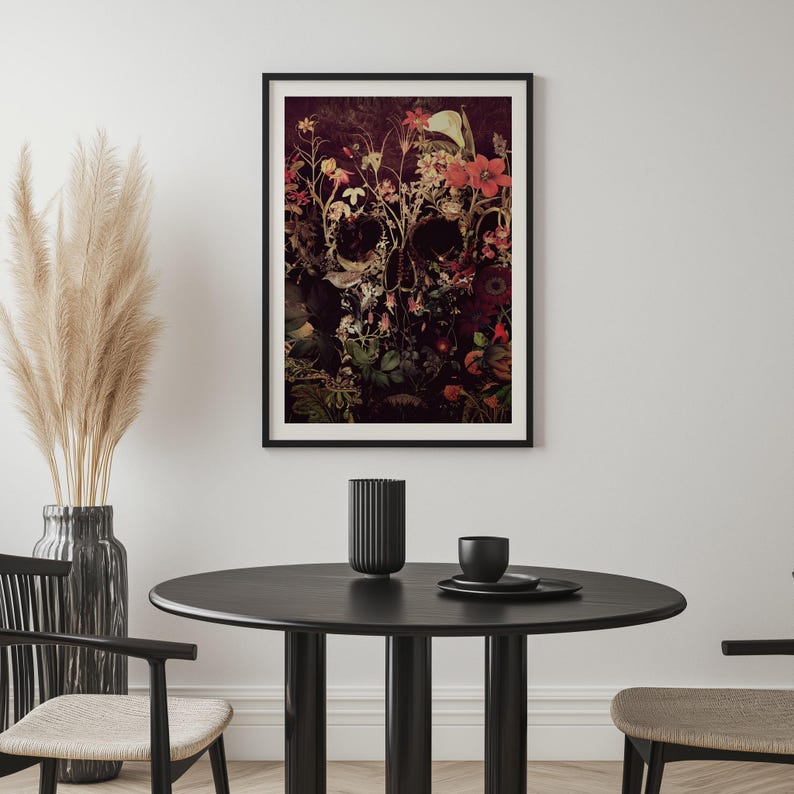 May include: A black framed print of a skull with flowers growing out of it. The skull is surrounded by a dark background with red, pink, and white flowers.