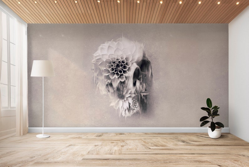May include: A grayscale wall mural featuring a skull design with floral elements. The artwork is displayed in a room with a wooden floor, a white floor lamp, and a potted plant. The room has a neutral color palette.