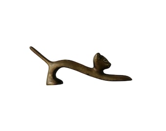 May include: A bronze sculpture of a stylised cat in a leaping pose. The cat's head is turned to the side, and its tail is curled up behind it.