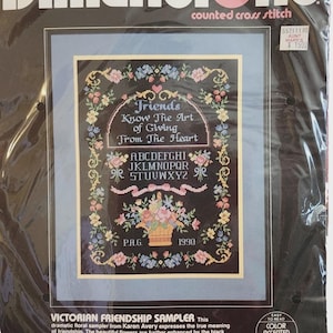 Può includere: Kit Dimensions per punto croce con un design di campionario di amicizia vittoriana. Il tessuto nero mostra una composizione floreale, il testo "Friends Know The Art of Giving From The Heart" e un alfabeto. Il kit include filo, un ago e istruzioni.