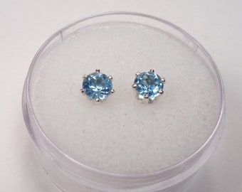 May include: A pair of silver stud earrings with light blue round gemstones.