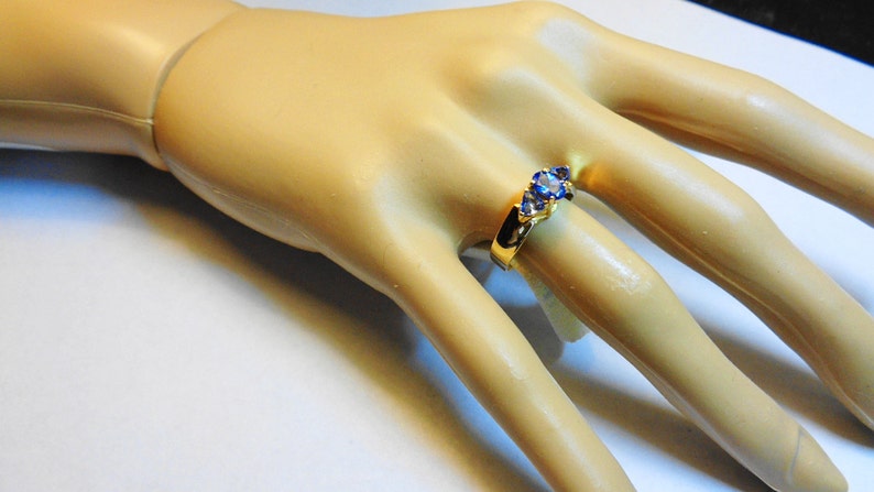 May include: A gold ring with three blue gemstones set in a curved band.