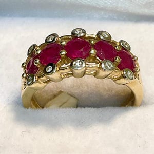 May include: A gold band ring with five ruby stones and small diamonds set in the band.