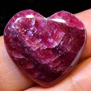 Può includere: Un cristallo di rubino lucido a forma di cuore, di colore rosso intenso e con una finitura scintillante e iridescente.