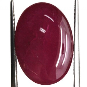 May include: A deep red oval cabochon gemstone. The gemstone is smooth and polished, with a high gloss finish.