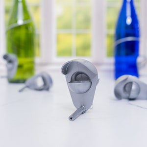 K&ouml;nnte beinhalten: Ein Satz von vier silbernen Flaschenverschl&uuml;ssen mit einem einzigartigen Design. Die Verschl&uuml;sse sind aus glattem, gl&auml;nzendem Metall gefertigt und haben eine kleine, runde &Ouml;ffnung oben. Die Verschl&uuml;sse sind perfekt, um Wein, &Ouml;l oder andere Fl&uuml;ssigkeiten frisch zu halten.