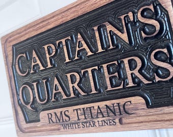May include: A wooden sign with black lettering that reads "Captain's Quarters" and "RMS Titanic White Star Lines".