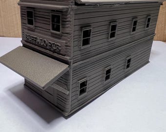 May include: A gray model of a two-story building with a flat roof and multiple windows. The building has a sign that reads "BUFFALO HUB". The model has a small awning extending from the front.