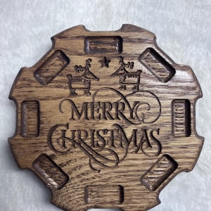 May include: A wooden Christmas decoration with the words "MERRY CHRISTMAS" carved in elegant script. The design includes reindeer and star motifs. The decoration has a unique shape with rectangular cutouts around the edges.