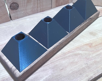 May include: A wooden candle holder with four dark blue pyramid-shaped candle holders. The candle holders are set in a rectangular wooden base. The wood has a natural grain and the candle holders are evenly spaced.