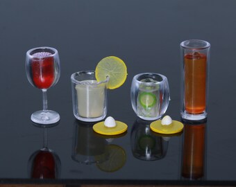 May include: Four clear glass drinkware pieces with different beverages. A red wine glass, a tall glass with a yellow drink and a lemon wedge, a glass with a green drink and a cucumber slice, and a tall glass with a brown drink.