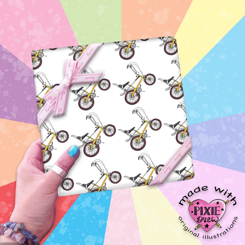 Op de afbeelding: Wit cadeaupapier met een herhalend patroon van gele en zwarte fietsen. Het cadeaupapier is vastgebonden met een roze lint met het woord "Love" erop gedrukt. Het cadeaupapier is gemaakt met originele illustraties van Pixie Drew.