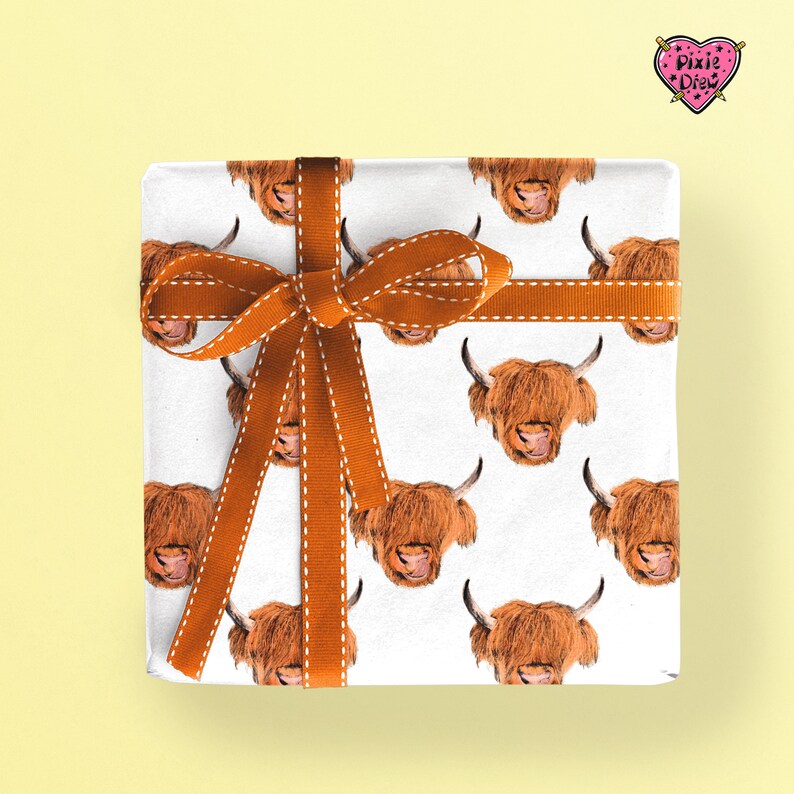 An illustration of a highland bull with it's tongue out in a repeat pattern wrapping paper with an orange ribbon