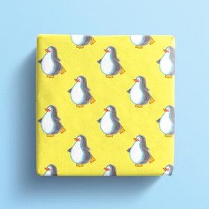 Pu&ograve; includere: Carta da regalo gialla con un motivo ripetitivo di pinguini. I pinguini sono neri e bianchi con becchi e piedi arancioni.