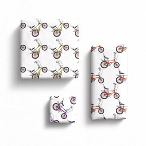 Op de afbeelding: Drie cadeaudozen met verschillende ontwerpen van vintage fietsen erop gedrukt. De dozen zijn wit met een witte achtergrond en de fietsen zijn in verschillende kleuren, waaronder geel, oranje en paars.