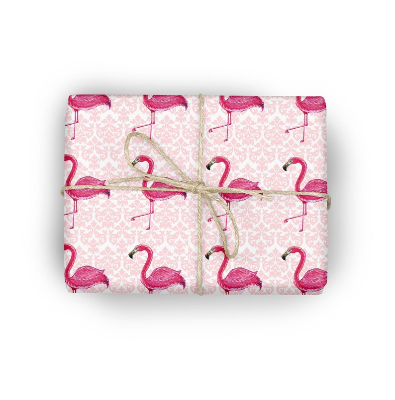 May include: Pink flamingo gift wrap with a white damask pattern. The wrapping paper is tied with twine.