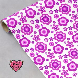 May include: A roll of wrapping paper featuring a repeating pattern of stylized flowers in various shades of magenta, purple, and light pink on a white background. A heart-shaped logo with the text Pixie Drew is visible in the corner.