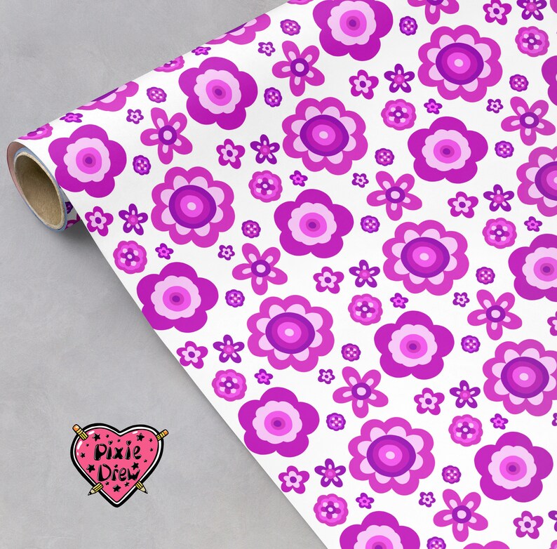 May include: A roll of wrapping paper featuring a repeating pattern of stylized flowers in various shades of magenta, purple, and light pink on a white background. A heart-shaped logo with the text Pixie Drew is visible in the corner.