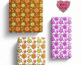 May include: Three rectangular blocks wrapped in patterned paper. One block has a brown background with orange and green flowers. Another has a white background with orange and green flowers. The third is white with purple flowers. A heart logo reads Pixie Drew.