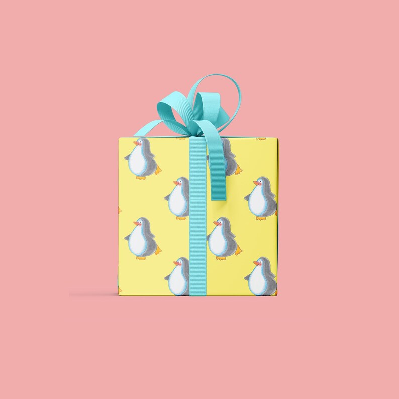 Pu&ograve; includere: Una scatola regalo gialla con un nastro blu e un motivo di pinguini.