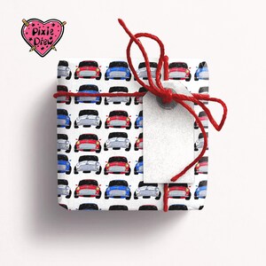 May include: A white gift box with a red ribbon and a tag. The box is wrapped in paper with a pattern of red, blue and white cars.