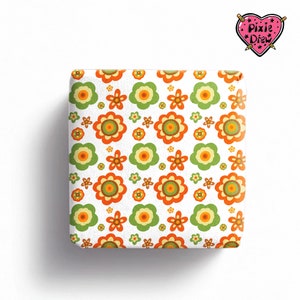 May include: A square-shaped object featuring a repeating pattern of stylized flowers in shades of orange, yellow, and light green on a white background. The top right corner displays a pink heart-shaped logo with the text Pixie Drew.